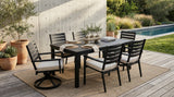 Outdoor dining set with table and chairs on a patio near a pool