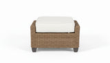 Wicker ottoman with a white cushion on a white background