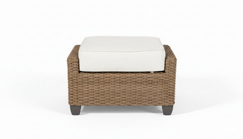 Wicker ottoman with a white cushion on a white background